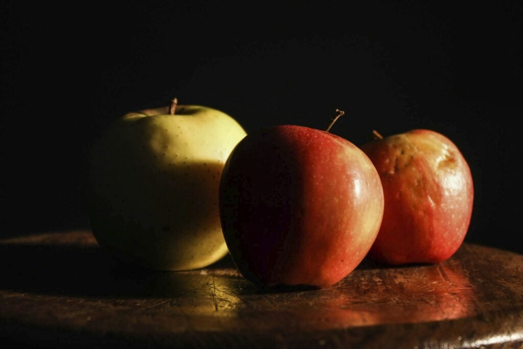 three apples sitting on top of a wooden table